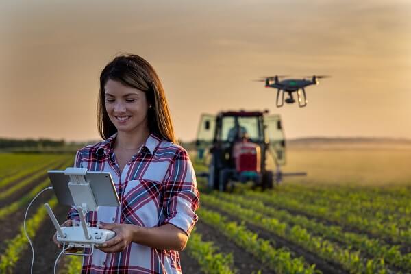 Mulher controlando drone que realiza pulverização da soja.