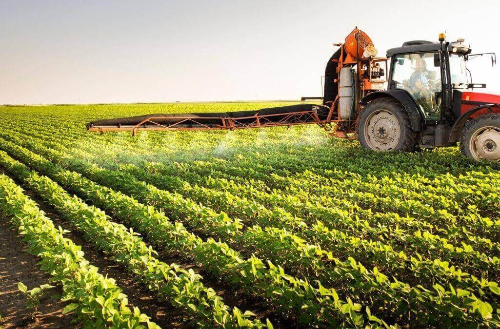 Seguro agrícola - trator pulverizando defensivos na lavoura de soja.