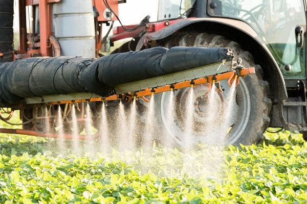 Maquinário realizando aplicação de herbicida pós-emergente para soja.